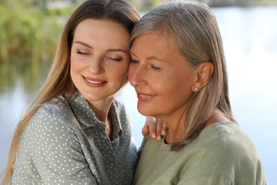 Photo of Family portrait of happy mother and daughter spending time together outdoors, closeup