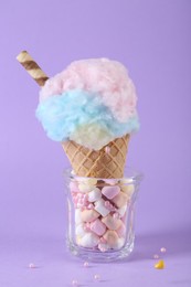 Photo of Sweet cotton candy in waffle cone on purple background, closeup