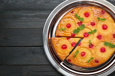 Delicious cut pineapple pie with cherry and mint on black wooden table, top view. Space for text