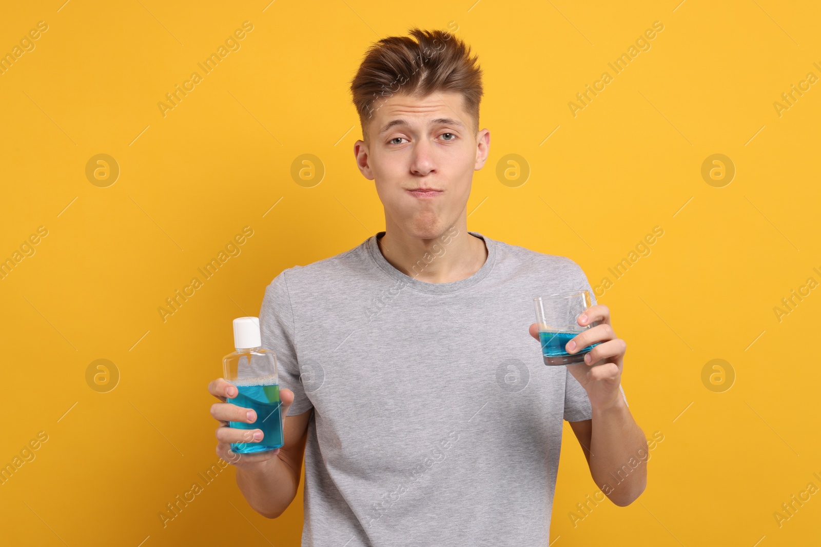 Photo of Young man using mouthwash on yellow background