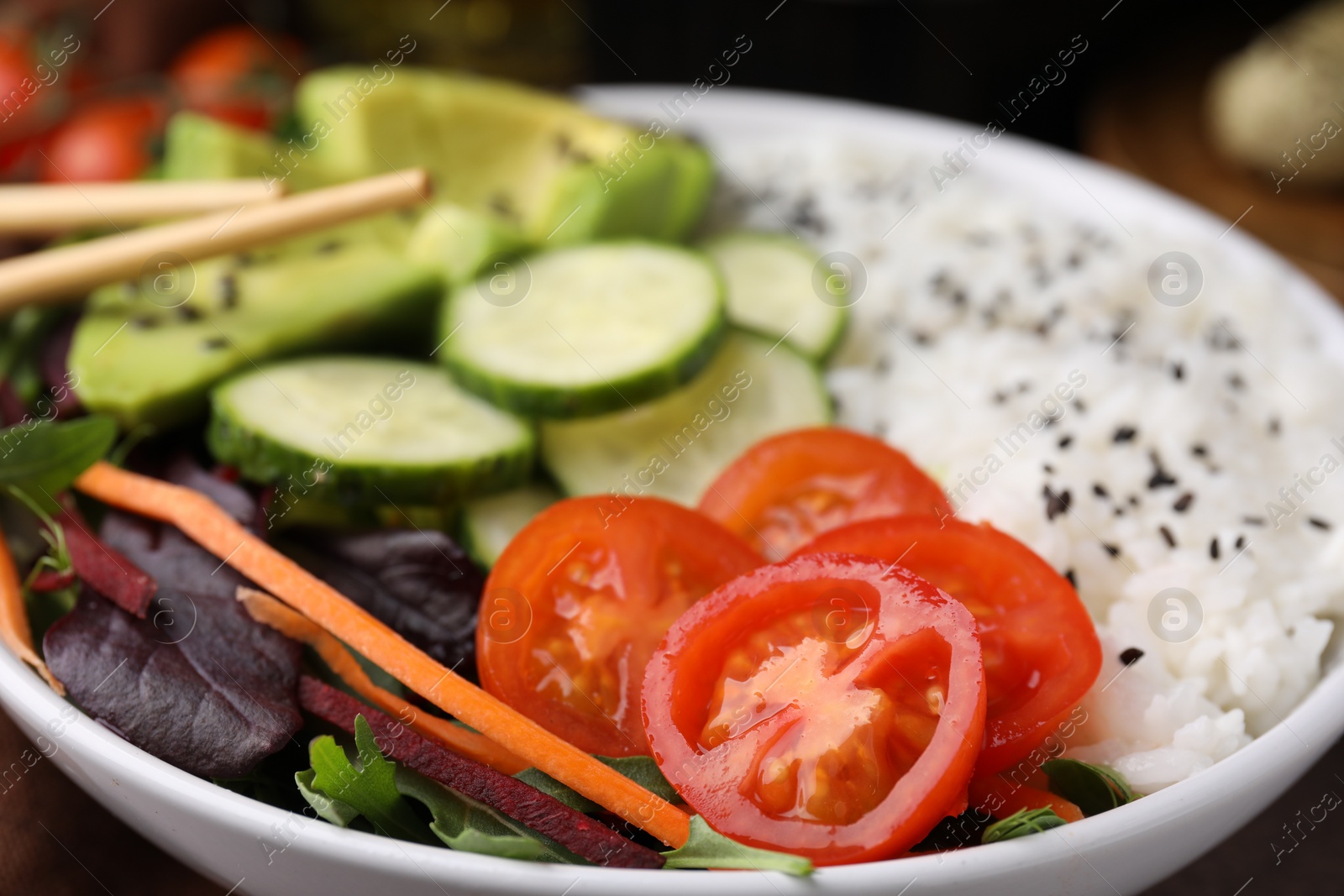 Photo of Delicious poke bowl with vegetables, avocado and mesclun, closeup