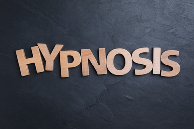 Photo of Word HYPNOSIS made with wooden letters on black background, flat lay