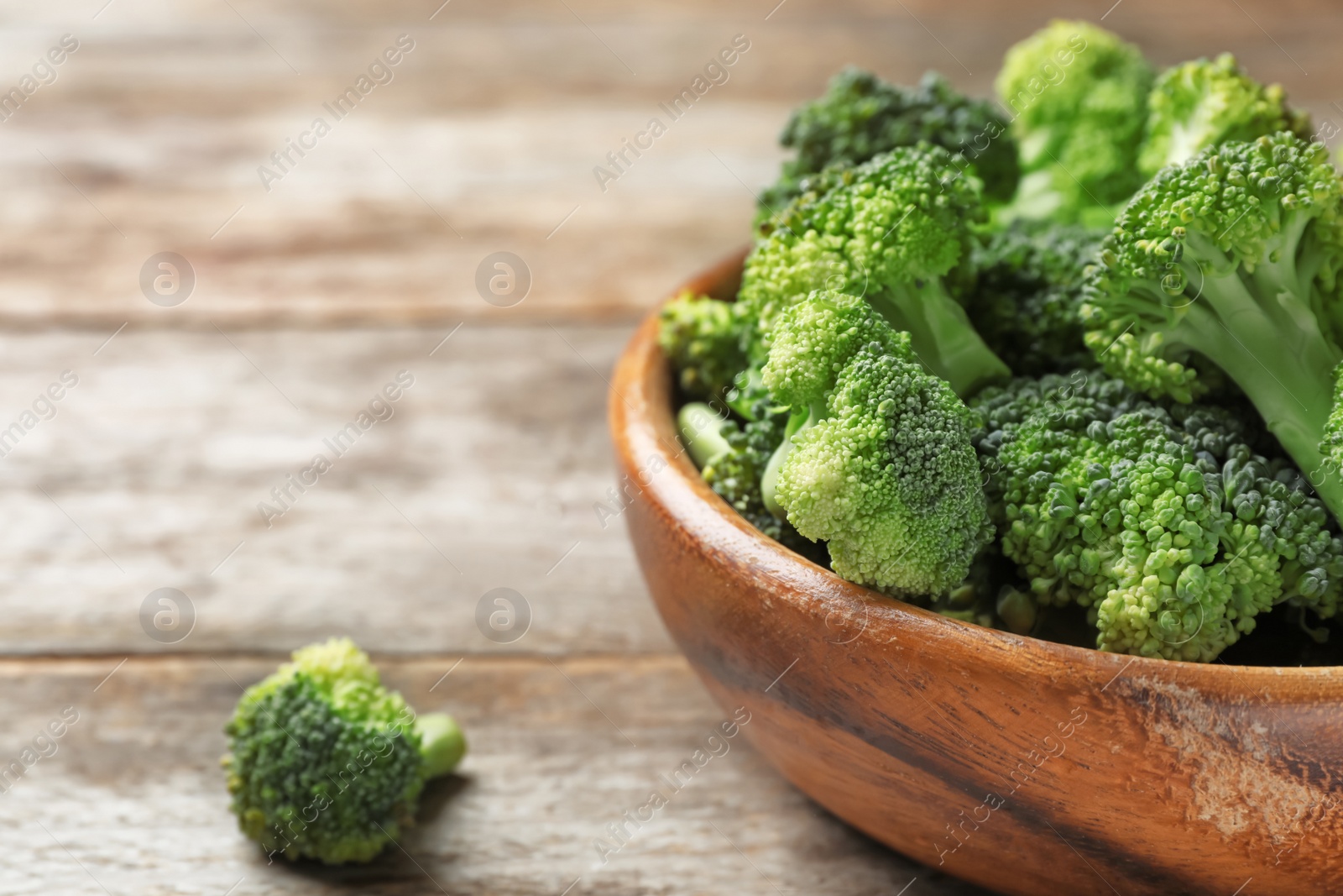 Photo of Bowl with fresh green broccoli on wooden table