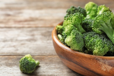 Photo of Bowl with fresh green broccoli on wooden table