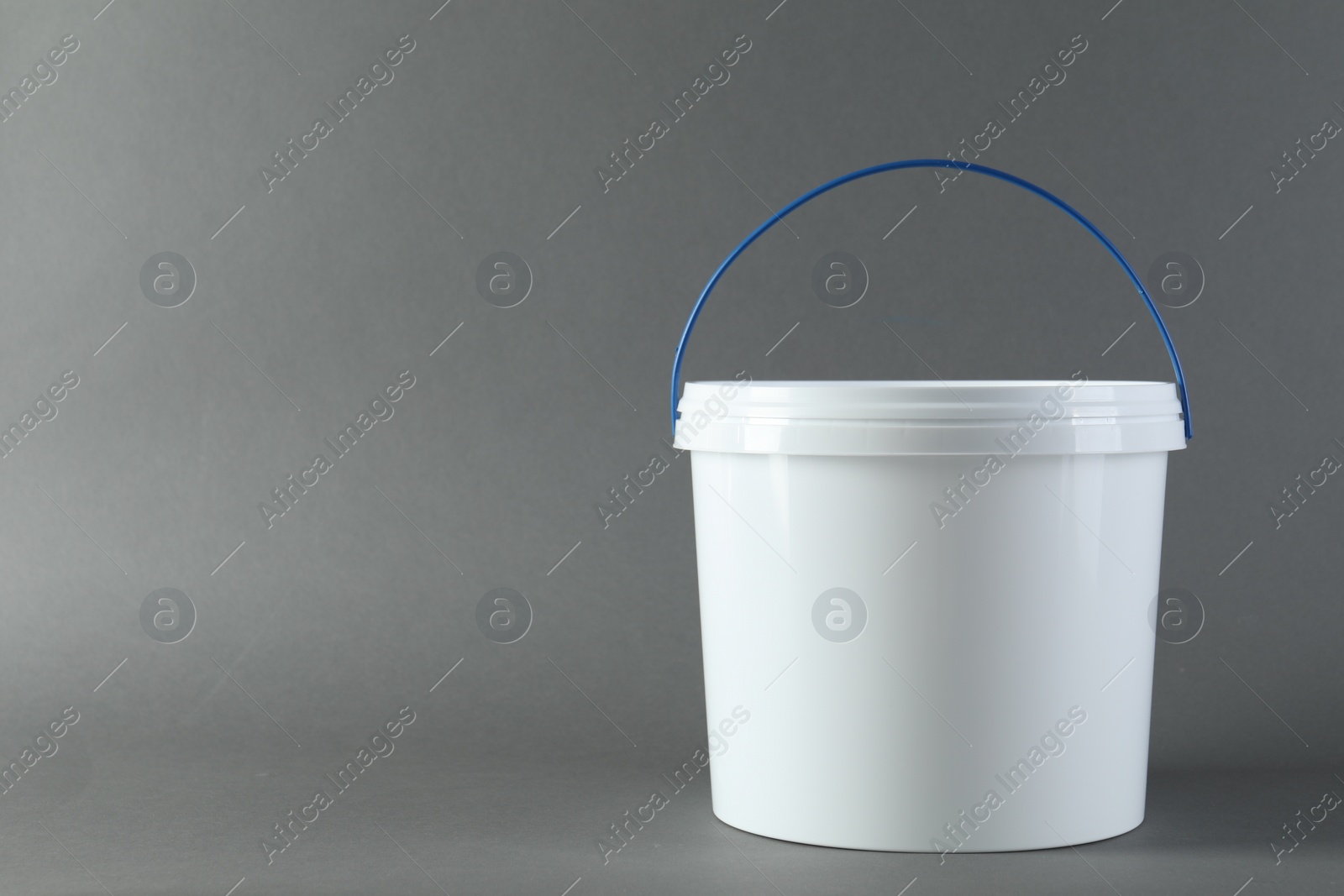 Photo of One plastic bucket with lid on grey background. Space for text