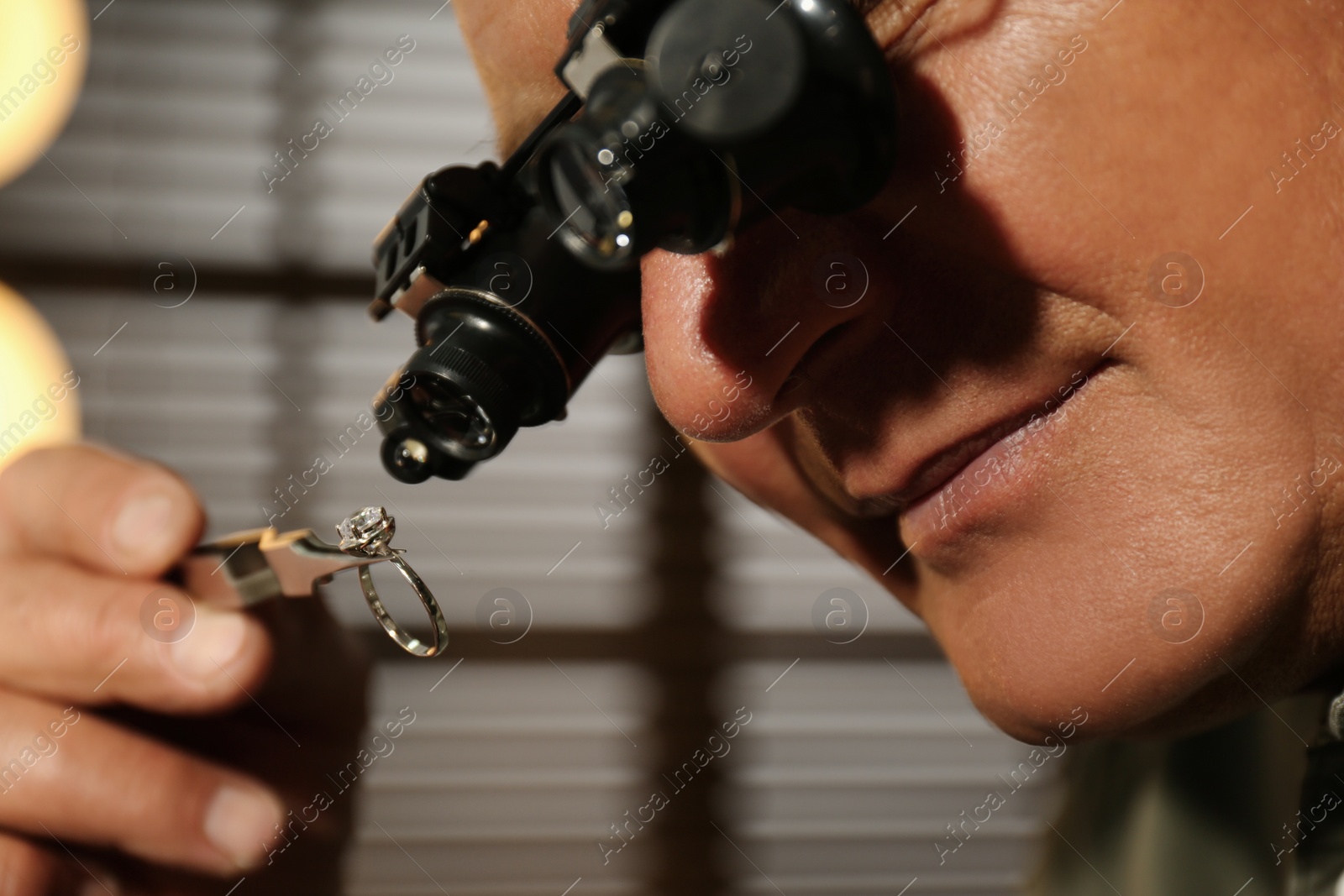 Photo of Professional jeweler working with beautiful ring indoors, closeup