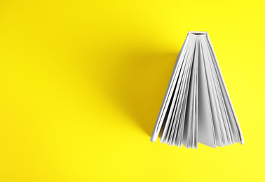 Hardcover book on yellow background, top view. Space for text