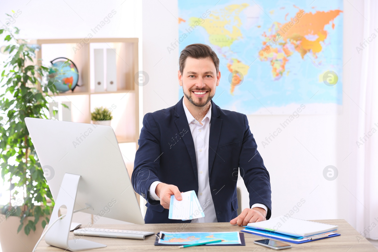 Photo of Male consultant holding tickets in travel agency