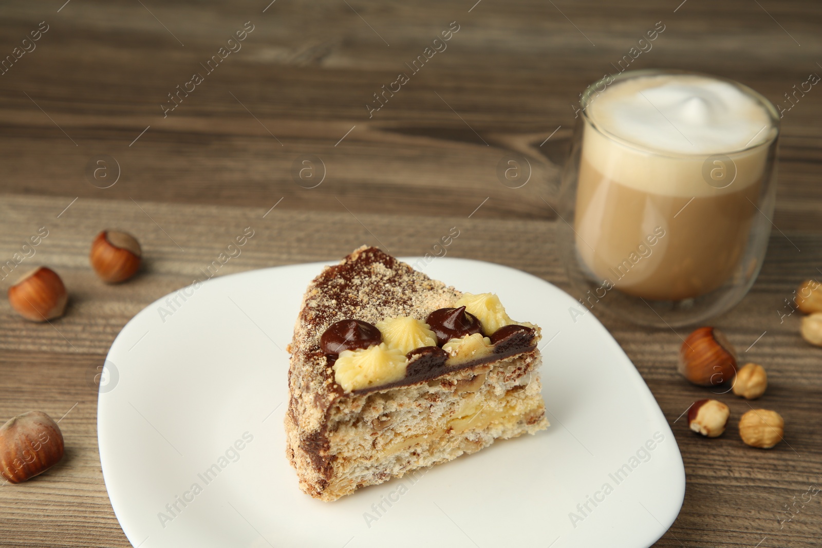 Photo of Piece of delicious Kyiv Cake served with coffee on wooden table, closeup