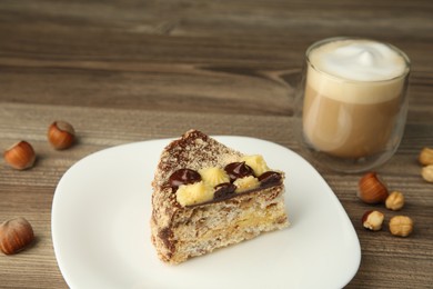 Piece of delicious Kyiv Cake served with coffee on wooden table, closeup