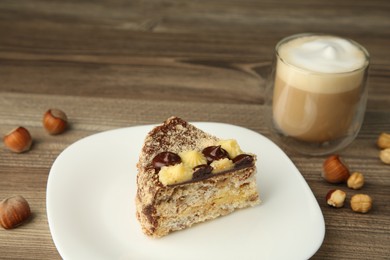 Photo of Piece of delicious Kyiv Cake served with coffee on wooden table, closeup