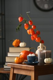 Beautiful autumn composition with cup of drink and pumpkins on wooden table indoors