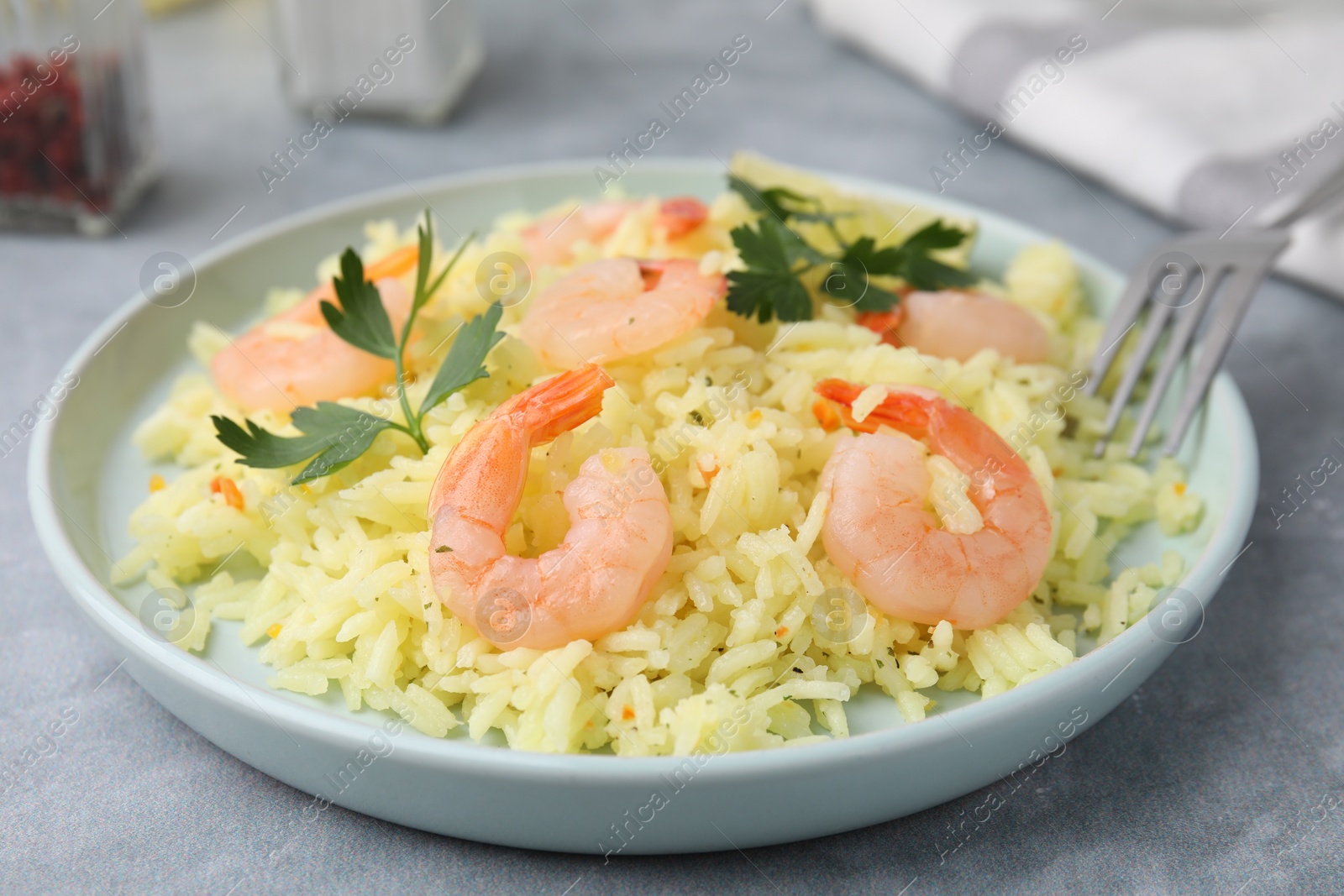 Photo of Delicious risotto with shrimps and parsley on light grey table, closeup