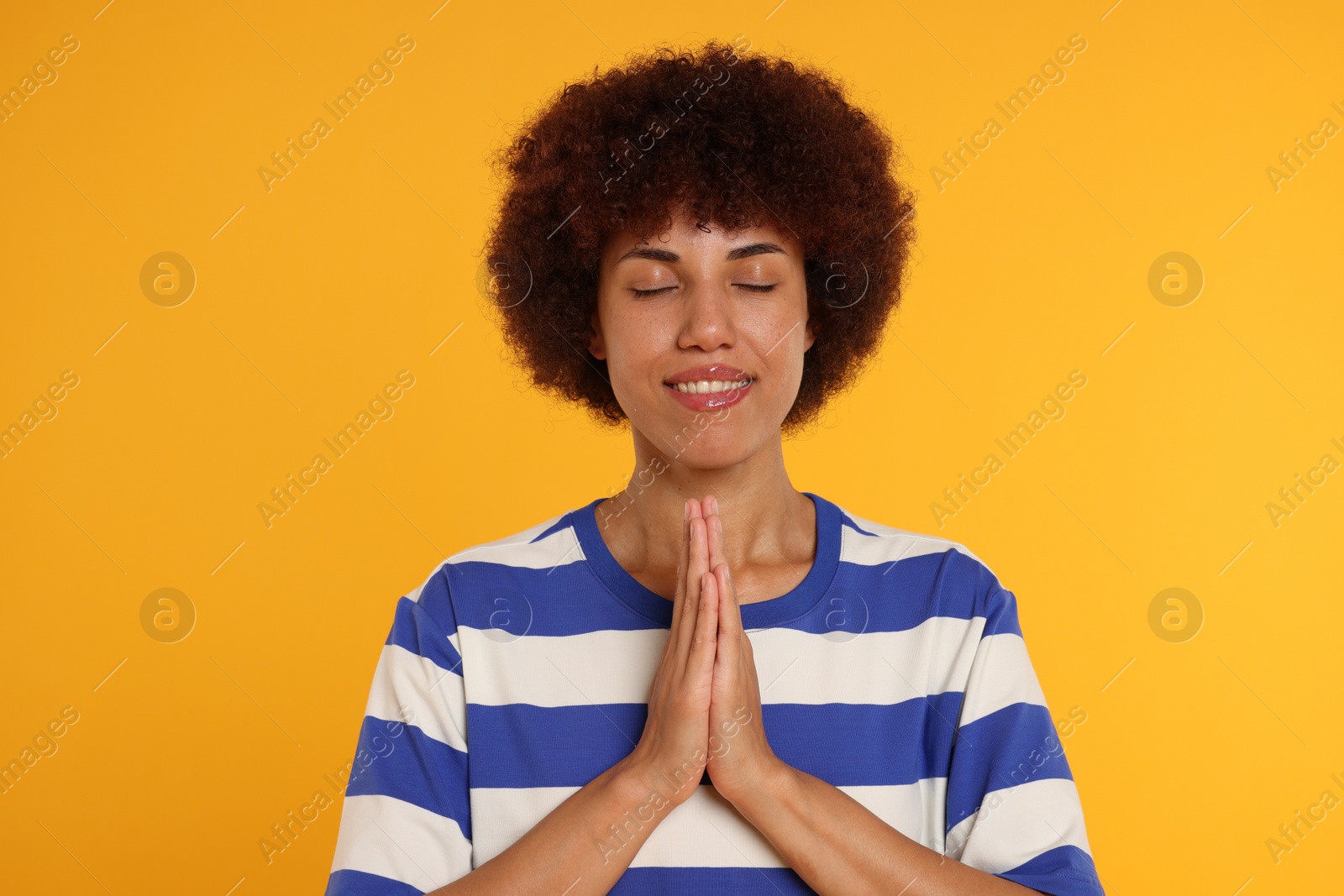 Photo of Woman with clasped hands praying to God on orange background