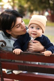 Mother kissing her baby on bench in park