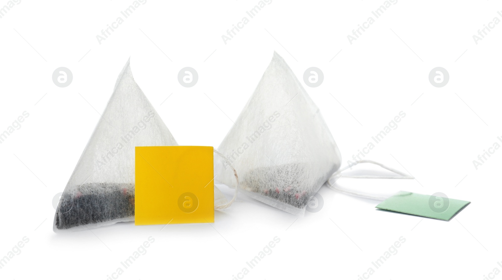 Photo of Unused pyramid tea bags with tags on white background. Space for text