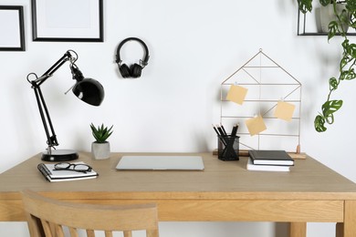 Photo of Home workplace. Laptop, lamp and stationery on wooden desk