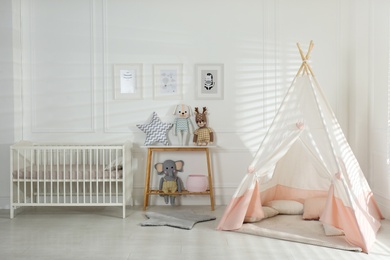 Photo of Comfortable crib and play tent in baby room. Interior design