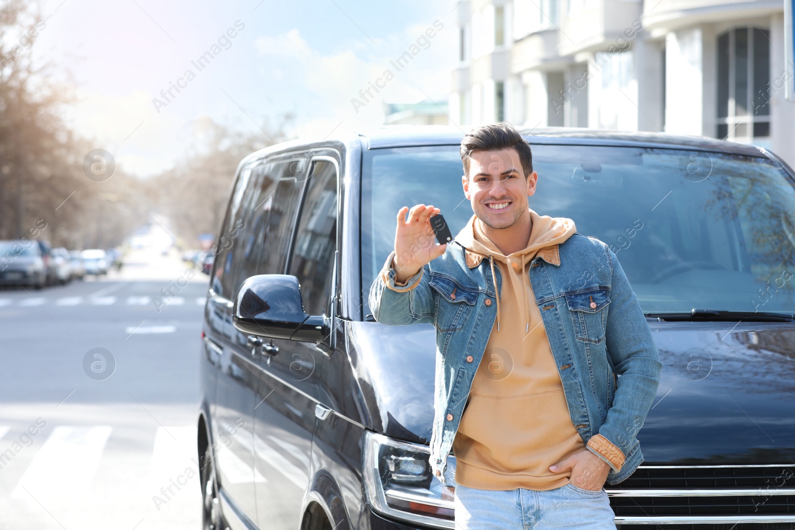 Photo of Man with key near car on city street. Buying new auto