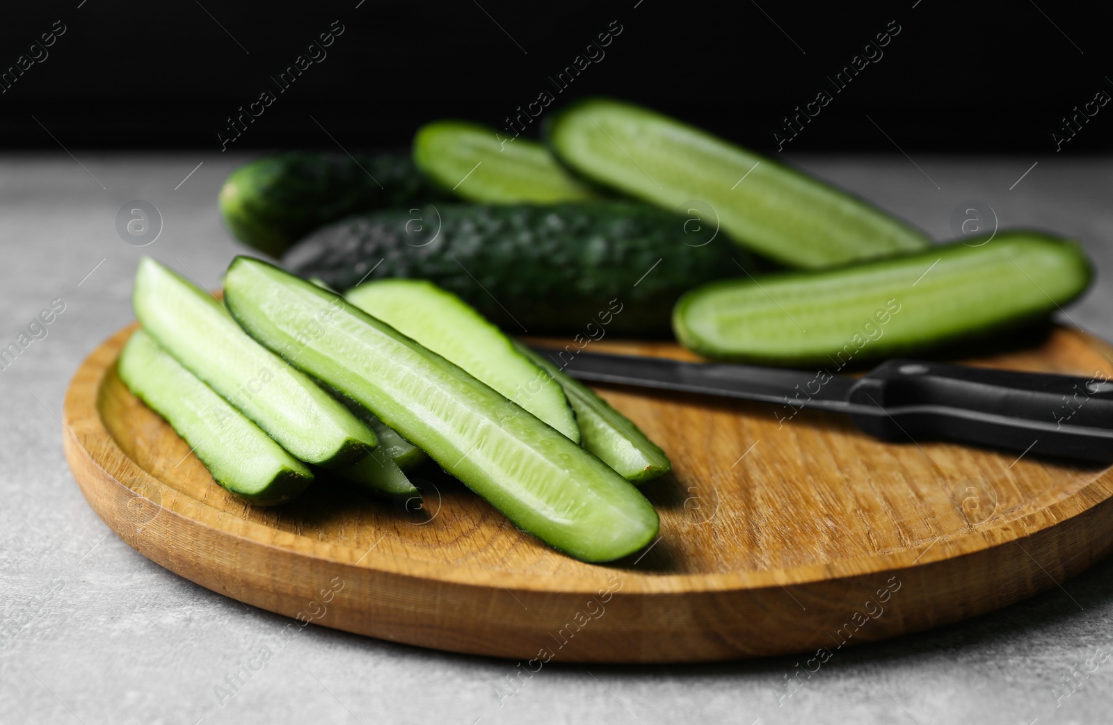 Photo of Whole and cut fresh ripe cucumbers on grey table