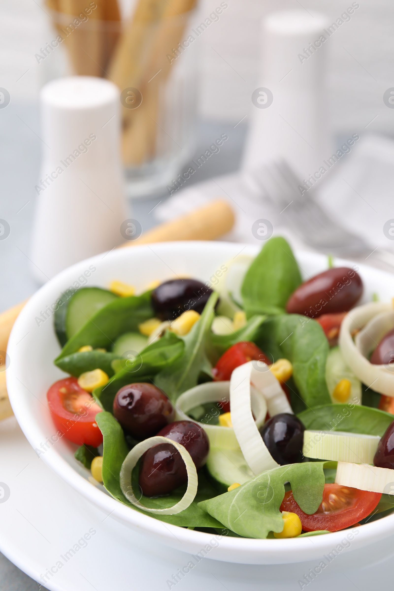 Photo of Bowl of tasty salad with leek and olives on table, closeup