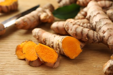 Photo of Cut turmeric roots on wooden table, closeup