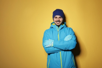 Photo of Young man wearing warm clothes on color background, space for text. Ready for winter vacation