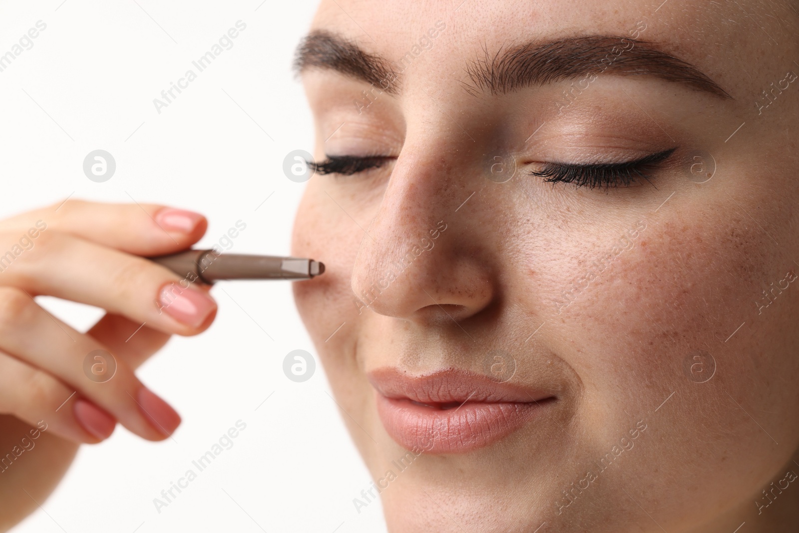 Photo of Beautiful woman drawing freckles with pen on white background, closeup