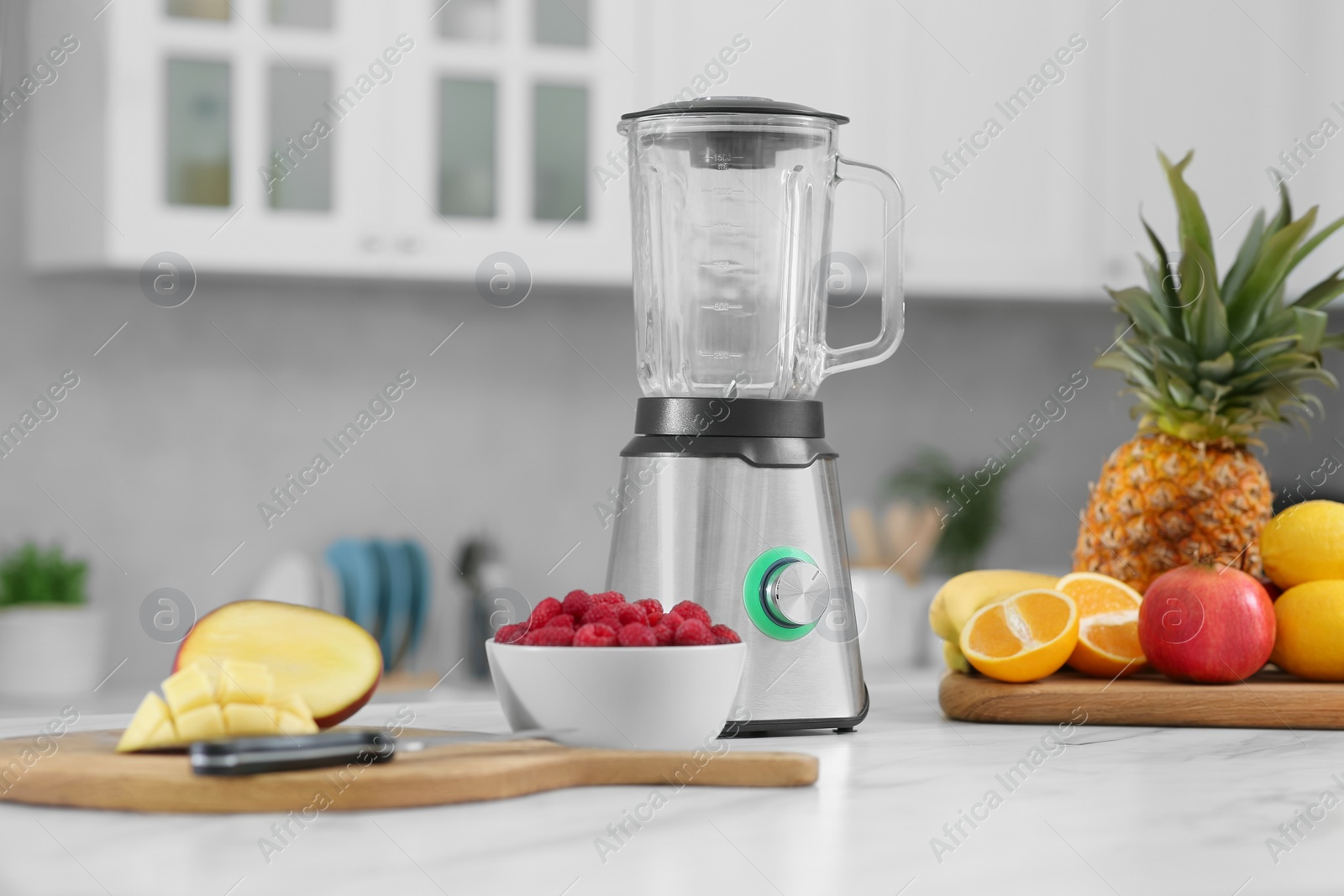 Photo of Blender and smoothie ingredients on white marble table in kitchen