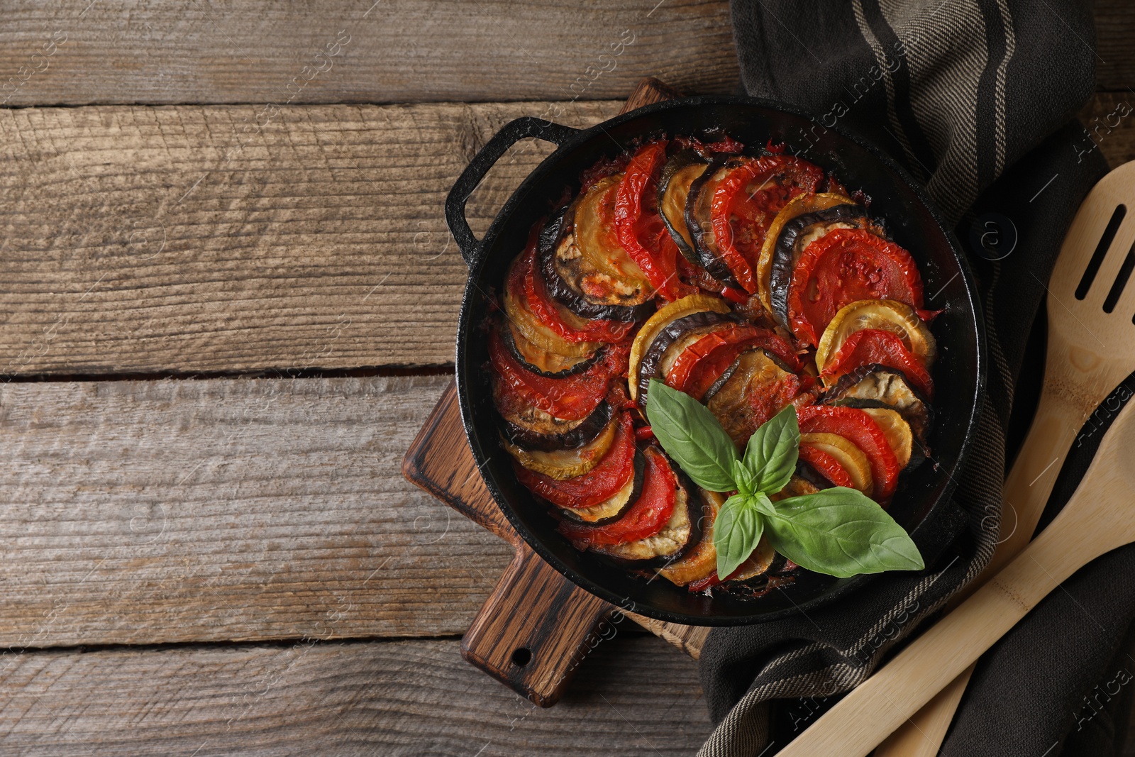 Photo of Delicious ratatouille and spatula on wooden table, top view. Space for text
