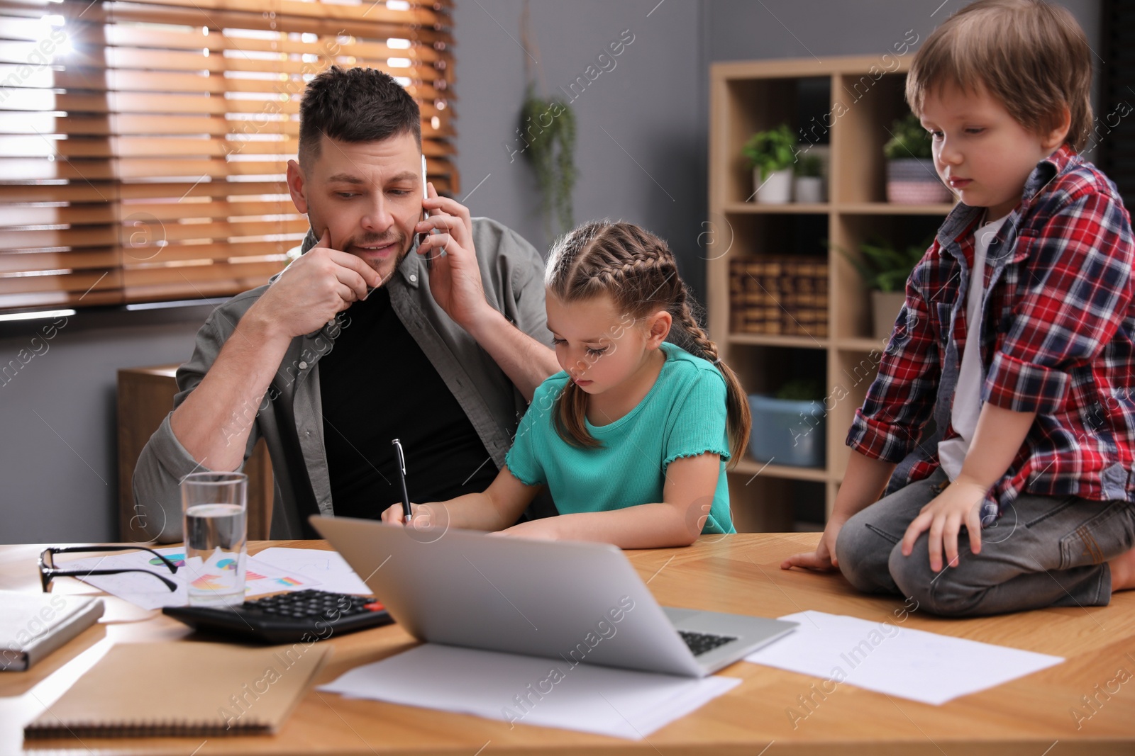 Photo of Overwhelmed man combining parenting and work at home