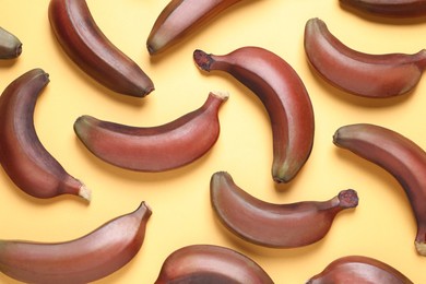 Tasty red baby bananas on yellow background, flat lay