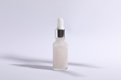 Photo of Bottle of cosmetic serum on white background