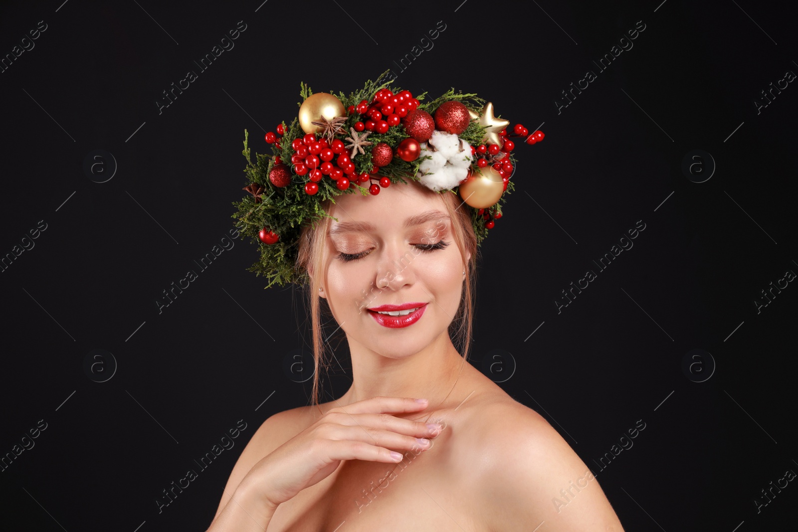 Photo of Beautiful young woman wearing Christmas wreath on black background