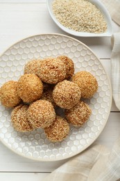 Delicious sesame balls on white wooden table, flat lay