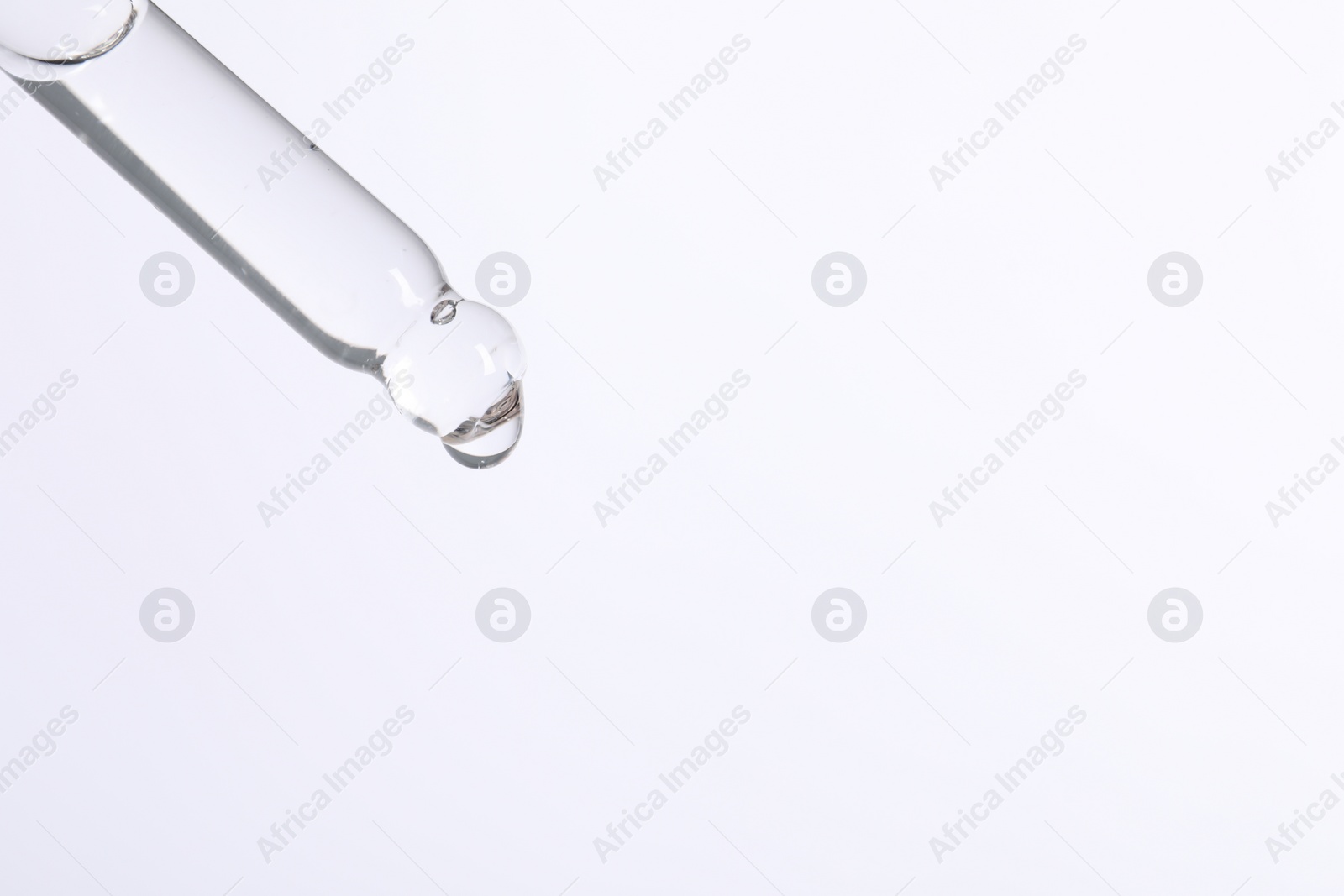 Photo of Dripping cosmetic serum from pipette on white background, space for text