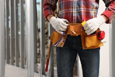 Photo of Professional builder with tool belt indoors, closeup