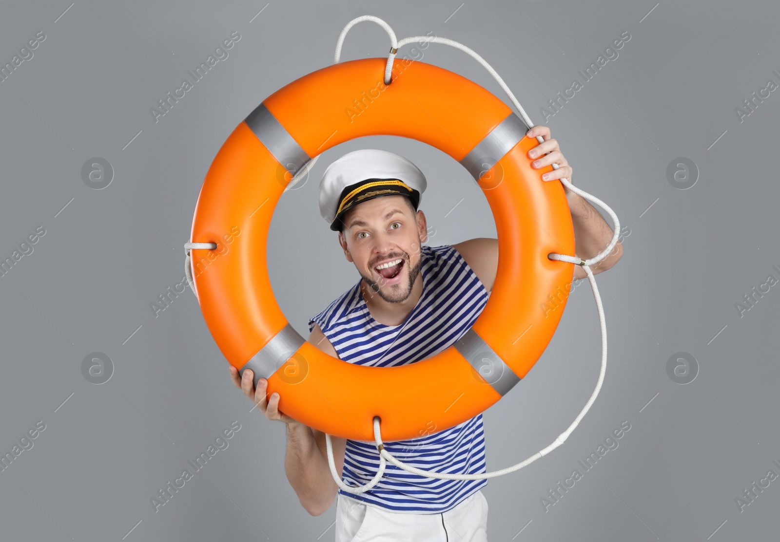 Photo of Happy sailor with orange ring buoy on grey background