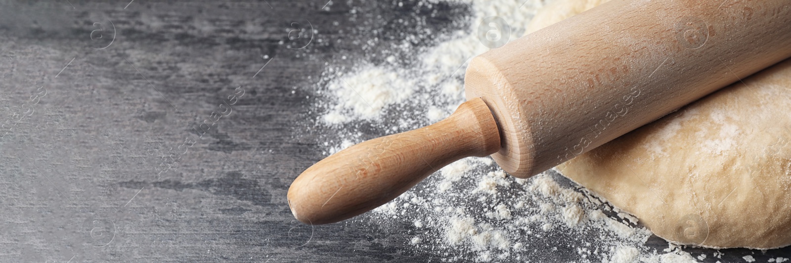 Image of Dough with rolling pin and flour on table, closeup. Banner design with space for text