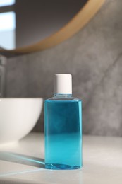 Photo of Bottle of mouthwash on light table in bathroom