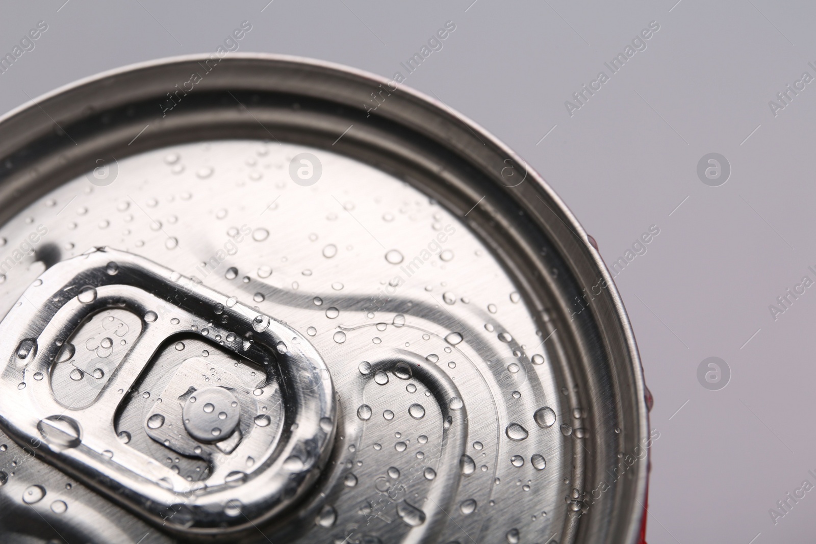 Photo of Energy drink in wet can on light grey background, closeup