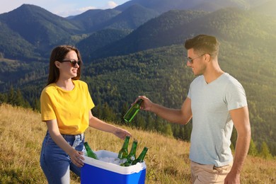 Couple and cool box with bottles of beer in mountains