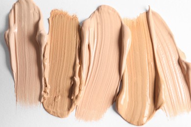 Photo of Samples of skin foundation on white background, closeup