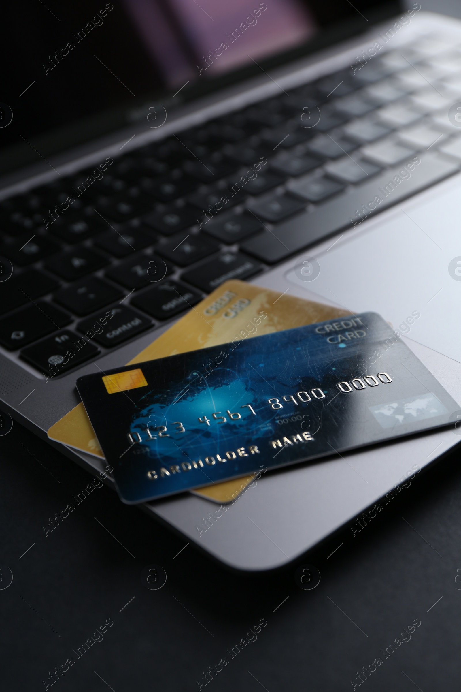 Photo of Laptop with credit cards on dark table, closeup