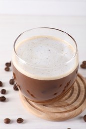 Photo of Refreshing iced coffee with milk in glass and beans on white table, closeup