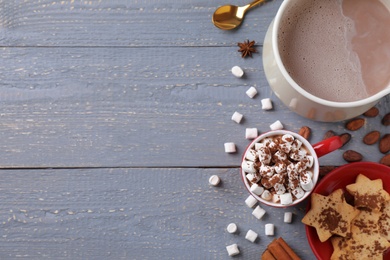 Flat lay composition of tasty cocoa with marshmallows on grey wooden table. Space for text