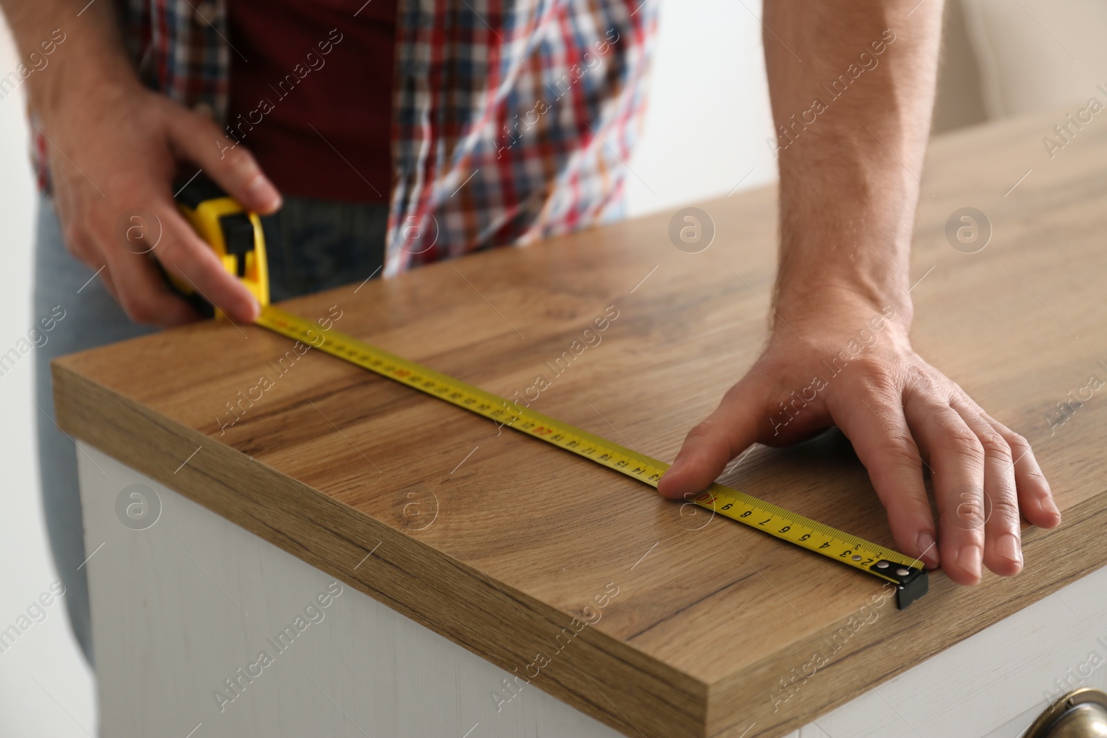 Photo of Man measuring wooden cabinet, closeup. Construction tool