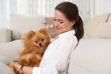 Photo of Happy young woman with cute dog in living room