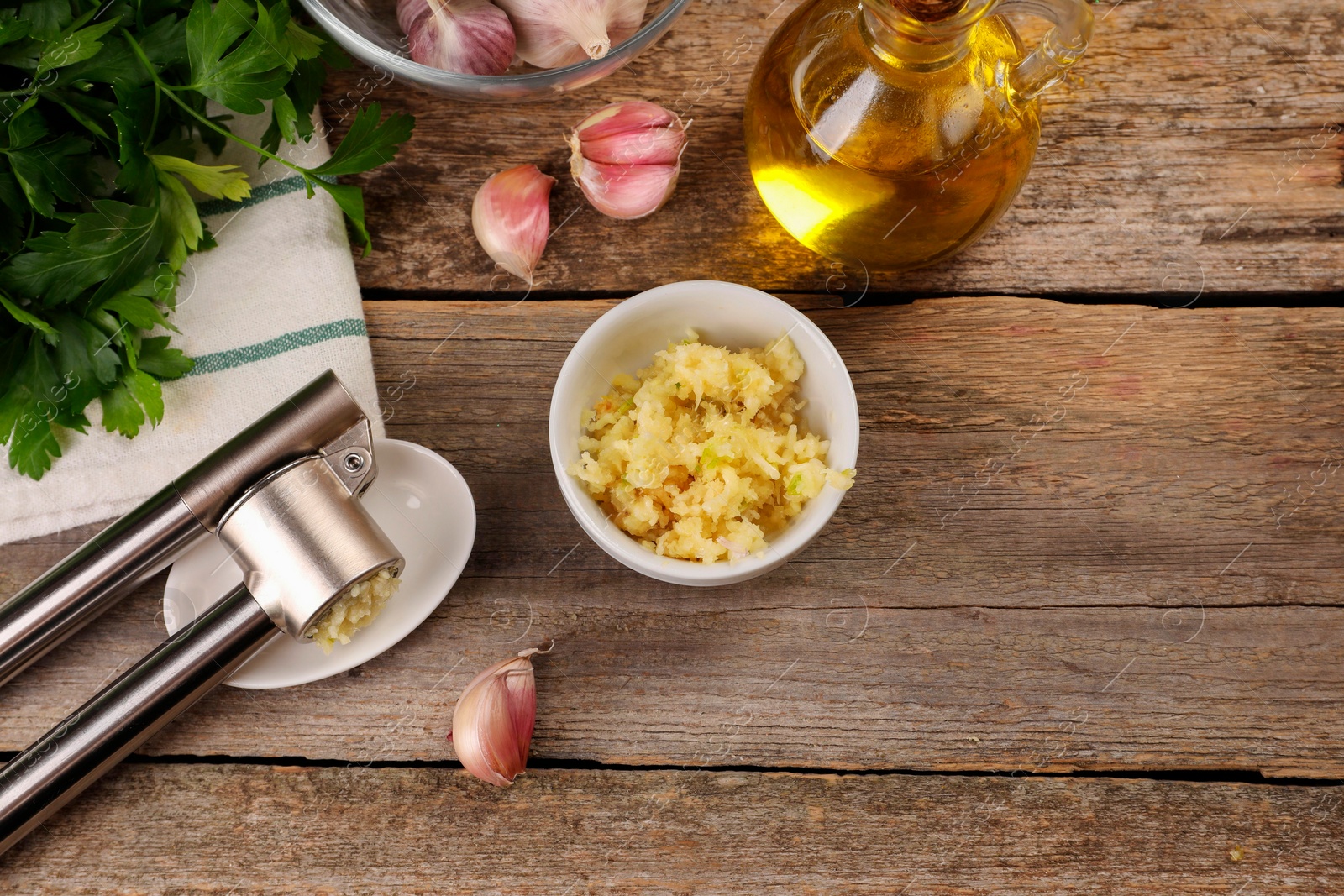 Photo of Garlic press and products on wooden table, flat lay. Space for text