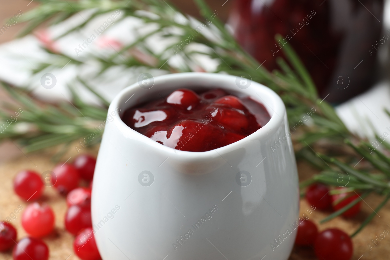 Photo of Cranberry sauce in pitcher and fresh berries on table, closeup